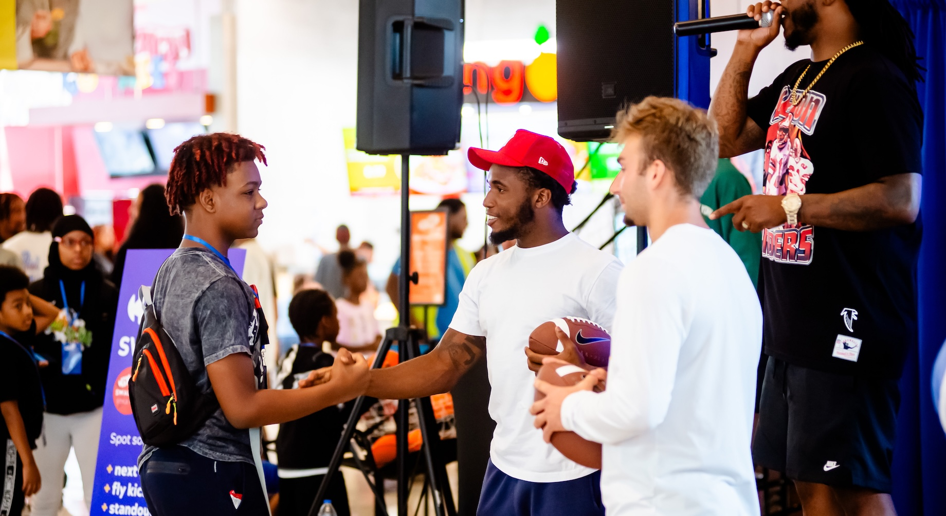 Toledo Rockets football players Junior Vandeross III, in the red hat, and Cooper Rusk, also holding a football, connected wit