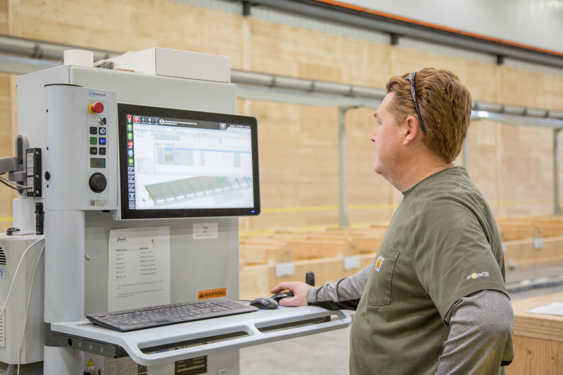 A worker operates a CNC, or computer numerical control machine, at Freres Engineered Wood in Lyons, Oregon.
