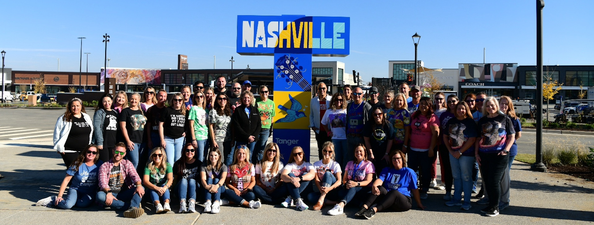 Leslie Swanson, in the green shirt leaning against the sign, on the eve of Tanger Outlets Nashville’s October grand opening. 