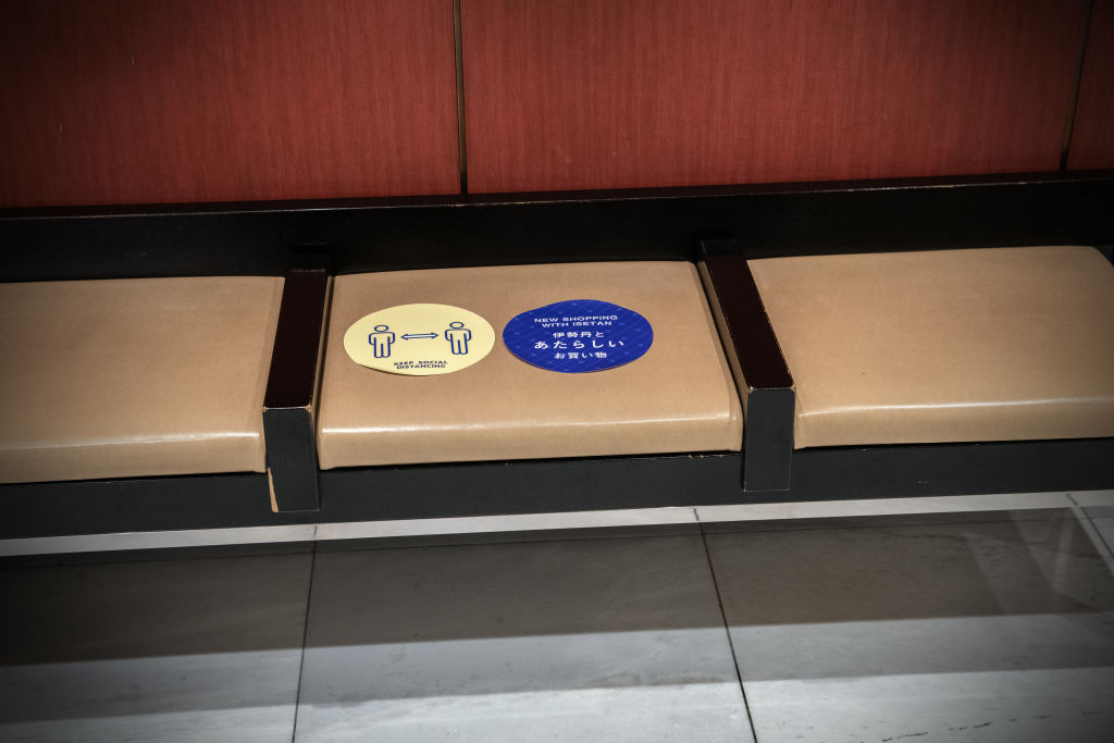 Signage reminds customers to practice social distancing, including while resting on this bench