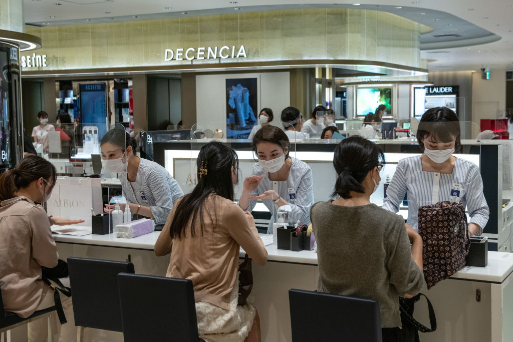 Staff members wear face masks while serving customers from behind plastic screens
