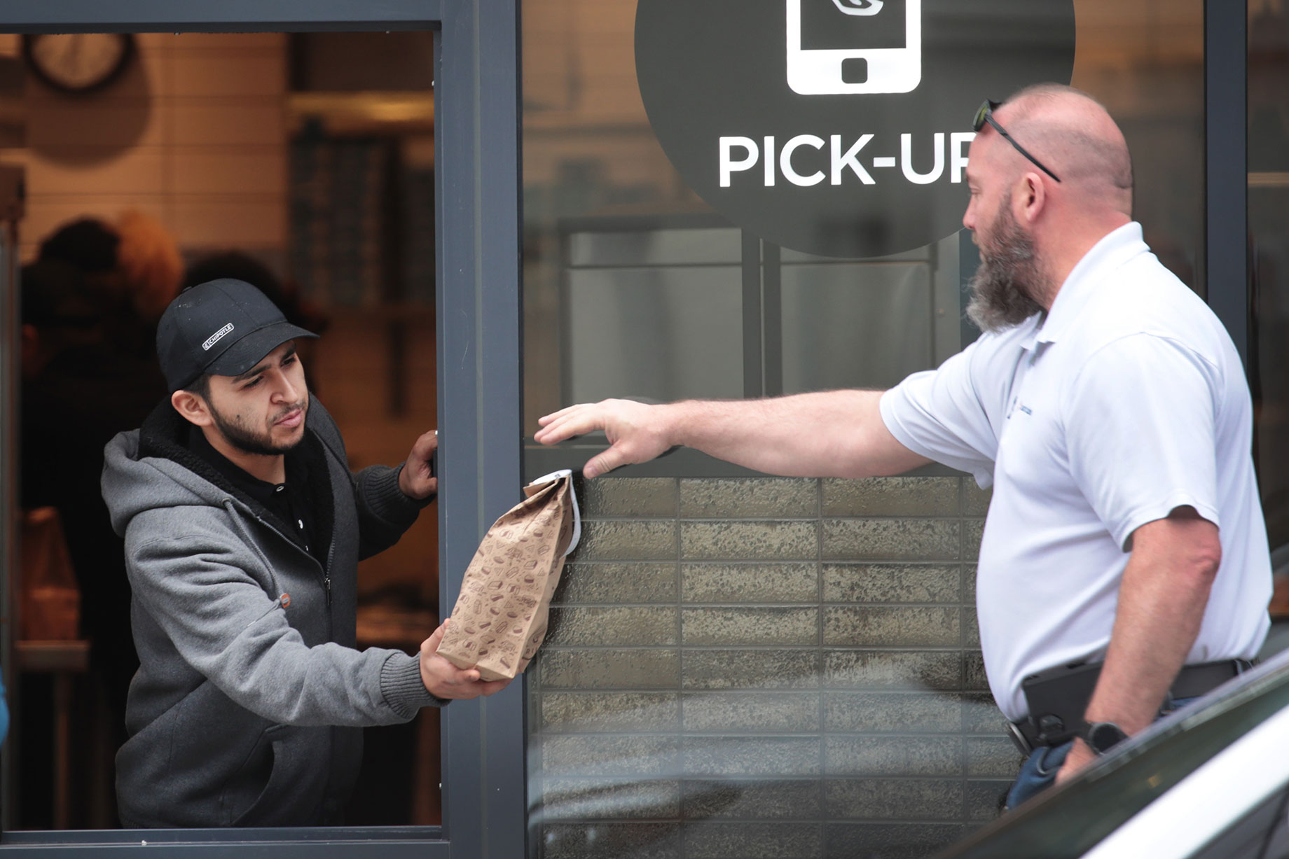 A Chicago Chipotle worker serves customers through a window. Illinois Governor JB Pritzker has ordered all restaurants and ba