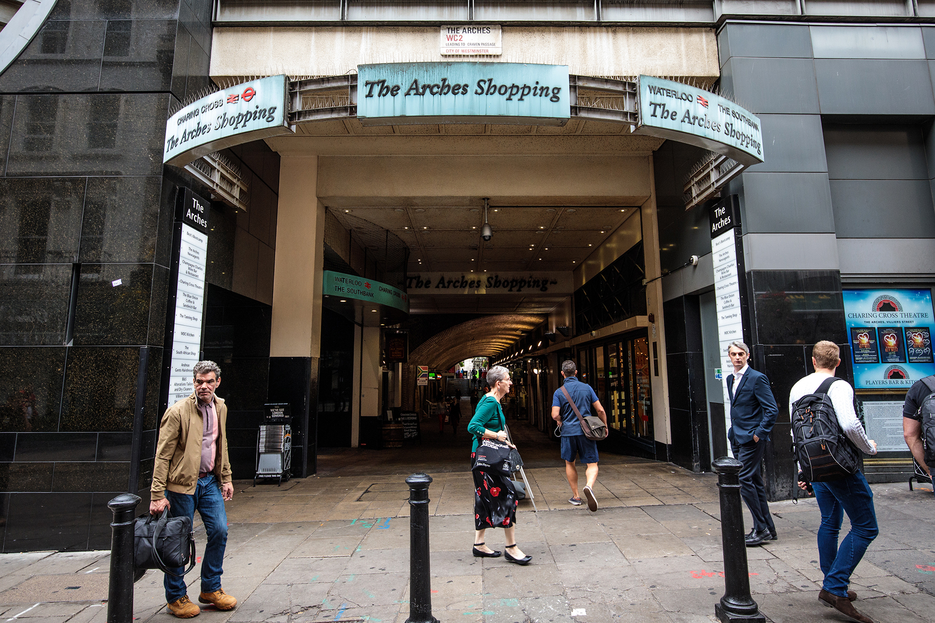 People walk past the Arches Shopping arcade, under Waterloo Station, in London